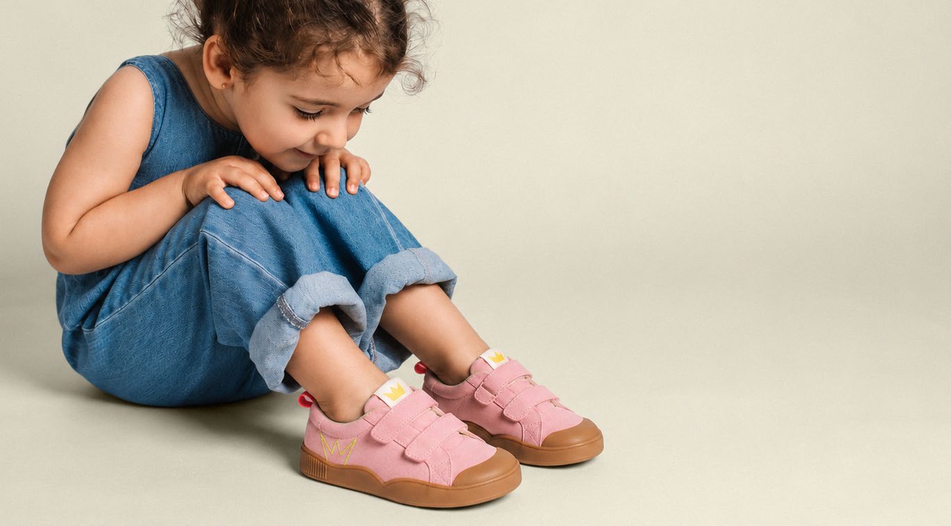 A little explorer in denim discovering her pink Petit Pace sneakers